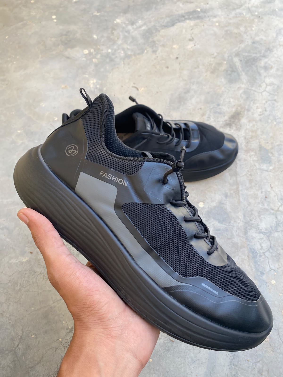 Black mesh fashion sneakers with thick cushioned soles and a toggle lace system